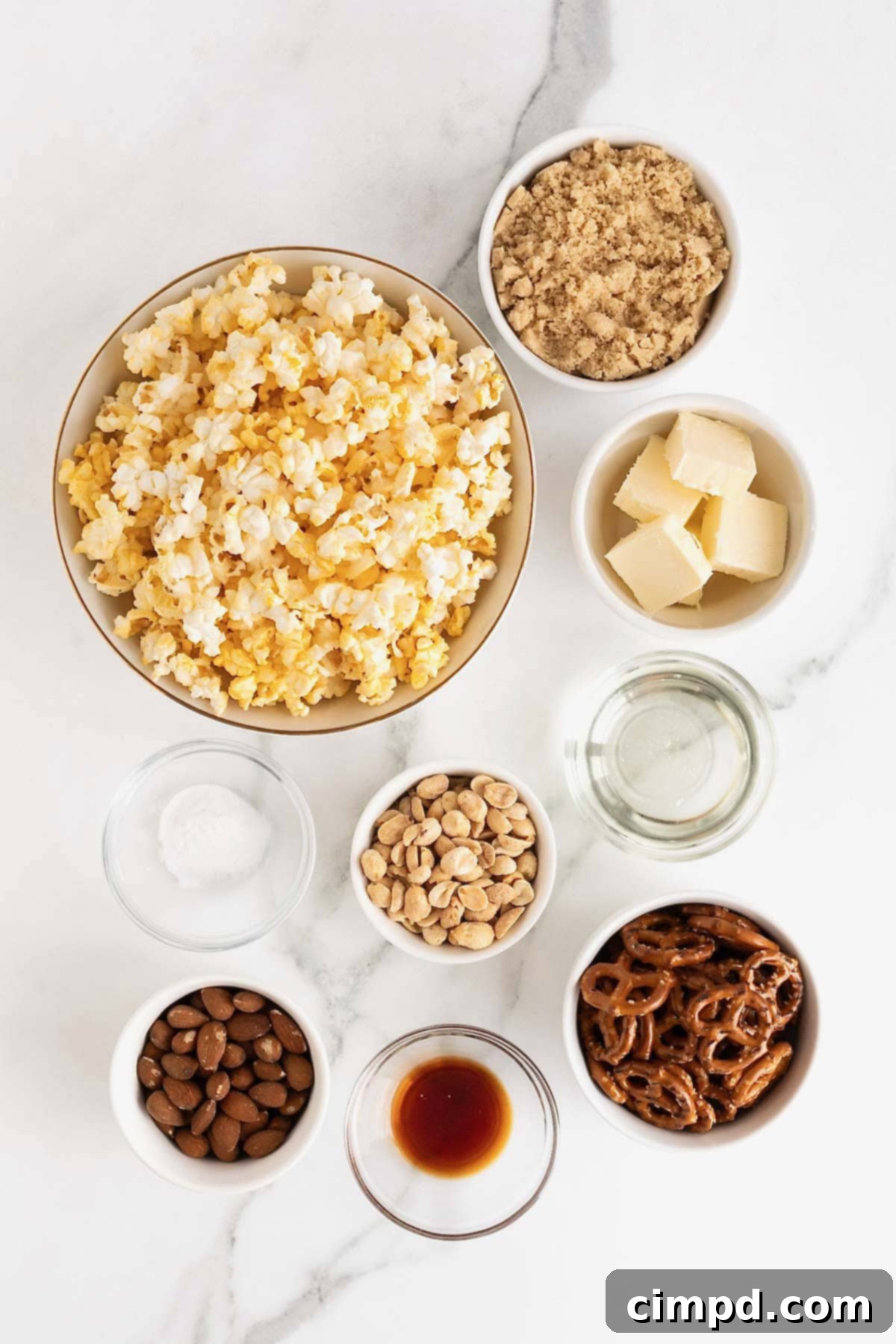 Ingredients to make caramel corn mix in small glass dishes on a white marble counter.