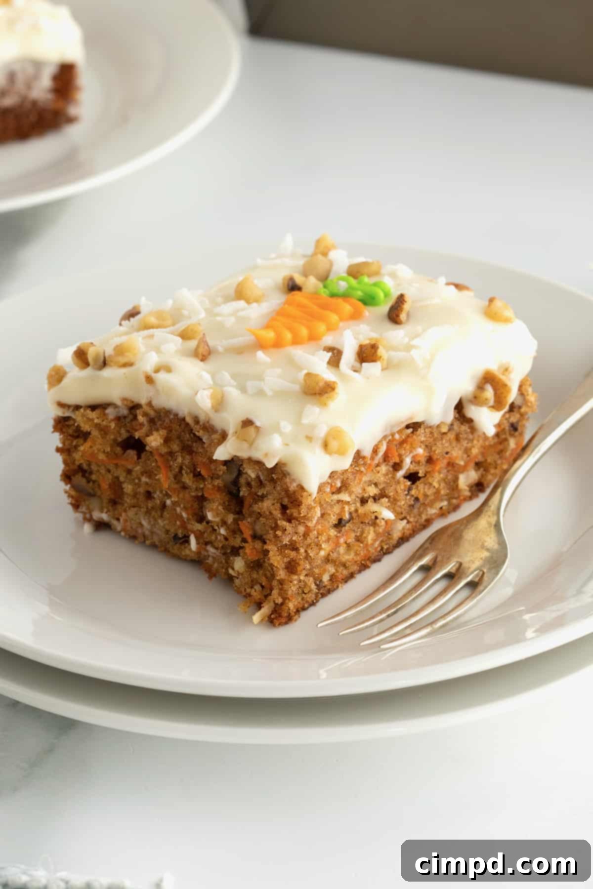 Perfectly Spiced Carrot Sheet Cake with Cream Cheese Frosting 3 Close-up of a slice of Carrot Sheet Cake with frosting, showcasing its moist texture, by The BakerMama