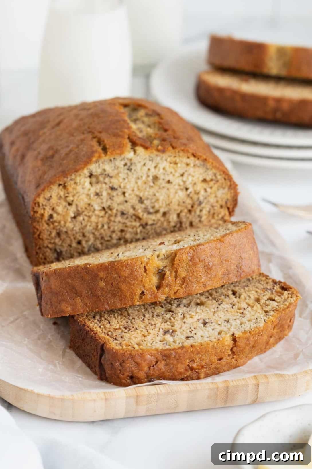 Next Level Brown Butter Banana Bread 2 A loaf brown butter banana bread loaf on a parchment covered wooden cutting board.