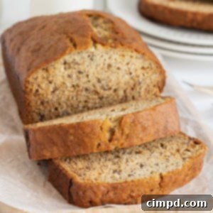 Next Level Brown Butter Banana Bread 15 A loaf brown butter banana bread loaf on a parchment covered wooden cutting board.