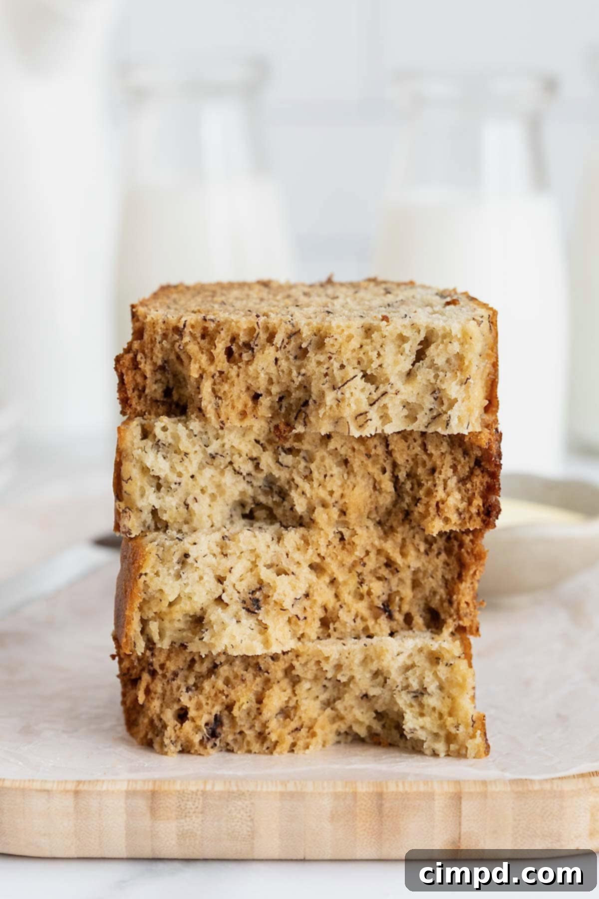 Next Level Brown Butter Banana Bread 4 A stack of four pieces of brown butter banana bread on a white surface.