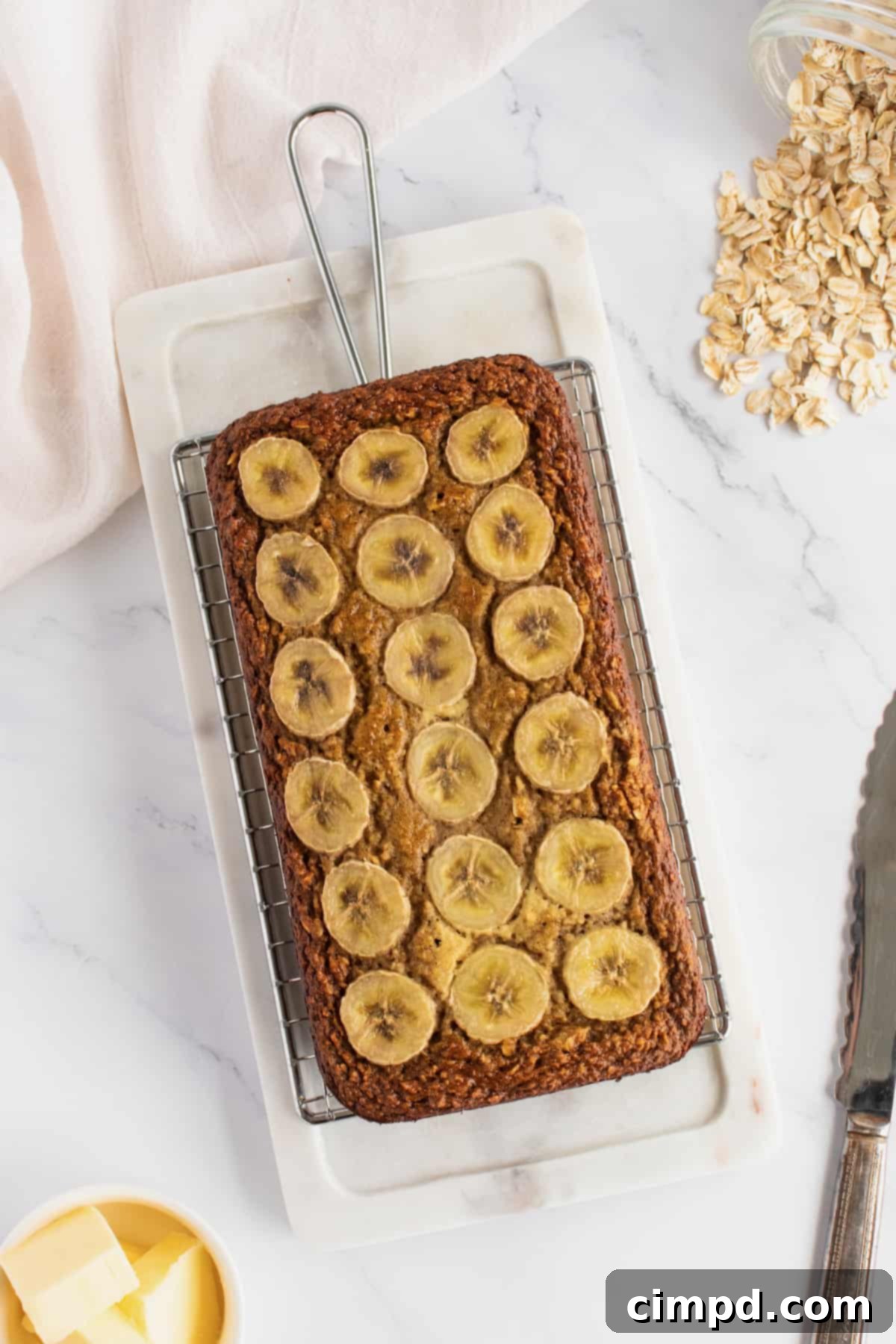 A freshly baked loaf of flourless banana bread resting on a marble cutting board, ready to be sliced.