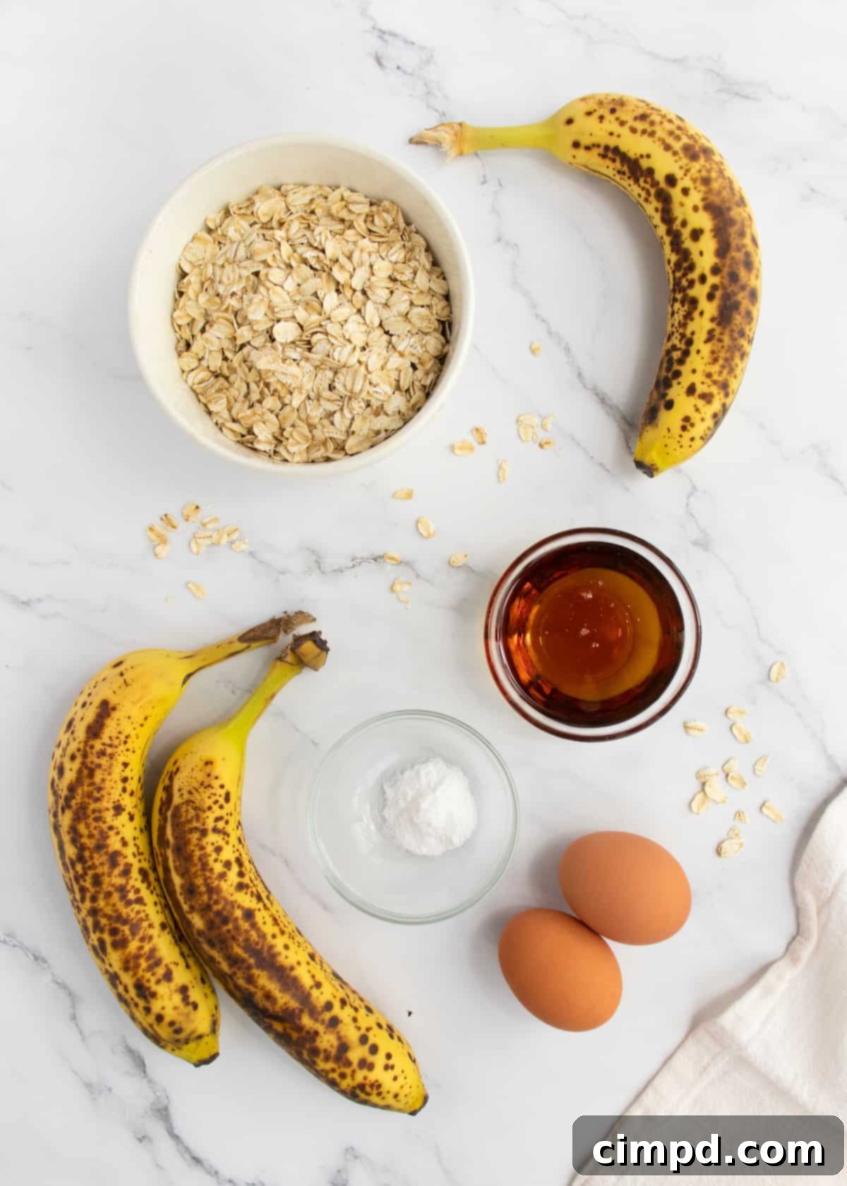 Five simple ingredients for flourless banana bread: bananas, eggs, maple syrup, baking soda, and rolled oats.