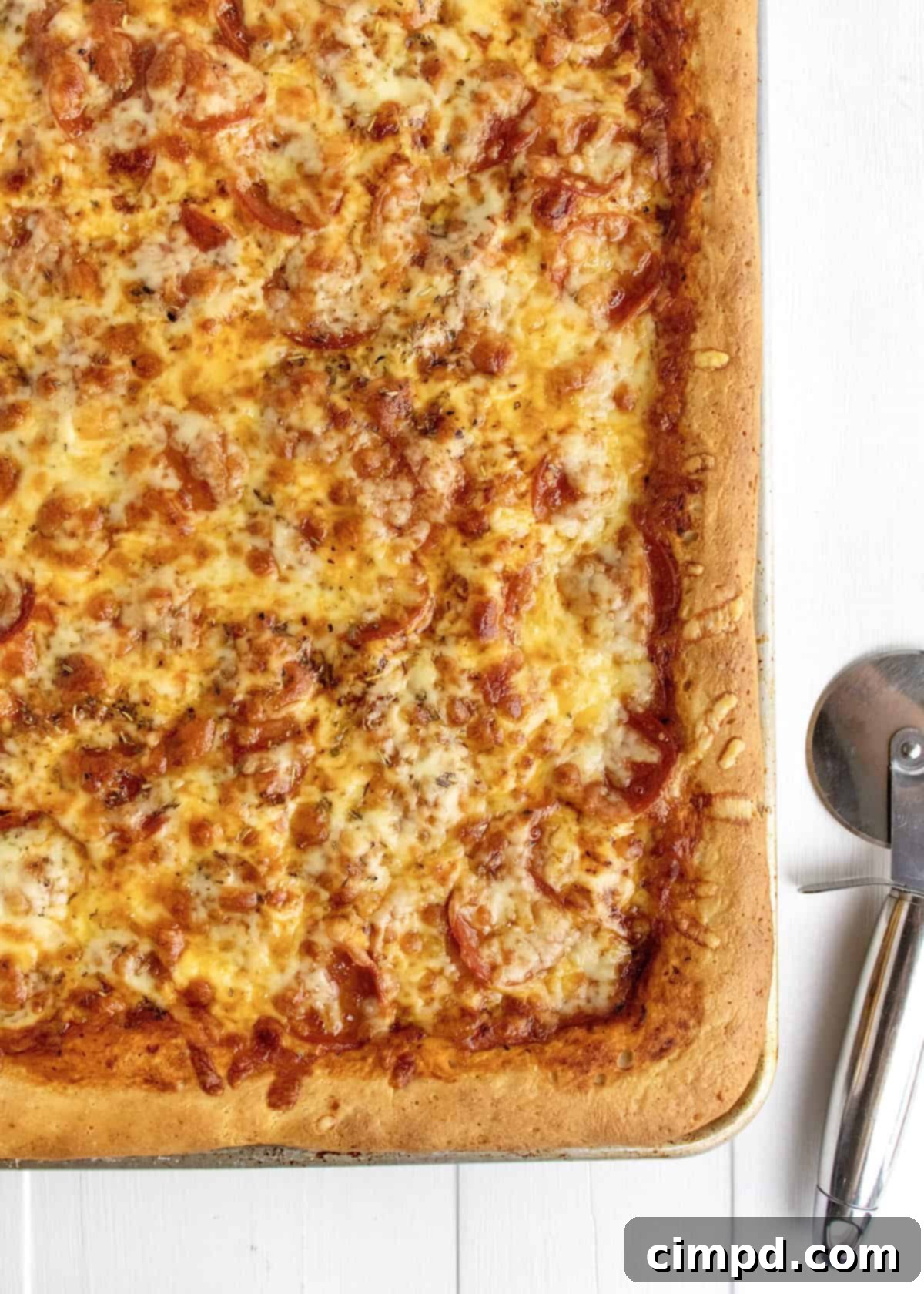 Tray-Baked Pizza Perfection 7 Close-up of a delicious slice of Sheet Pan Pizza with melted cheese and pepperoni.