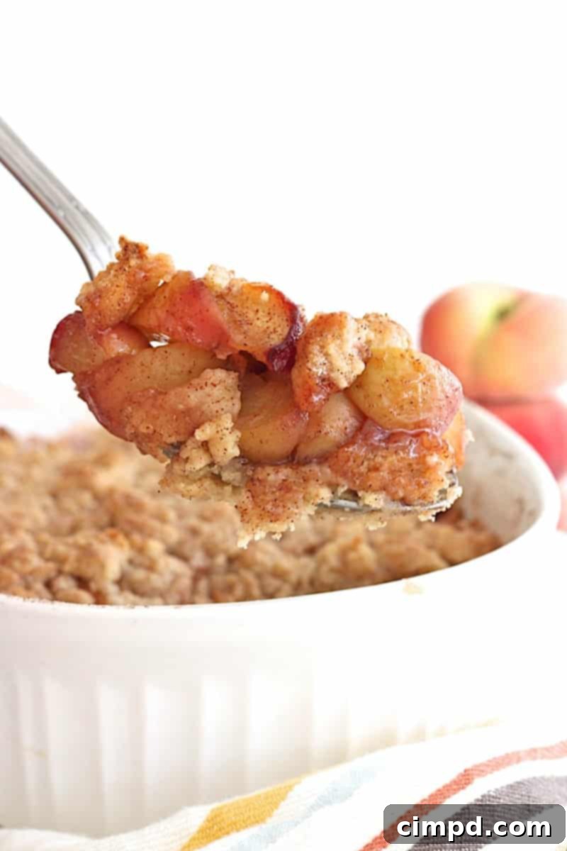 Slice of Snickerdoodle Peach Cobbler served with a scoop of melting vanilla ice cream