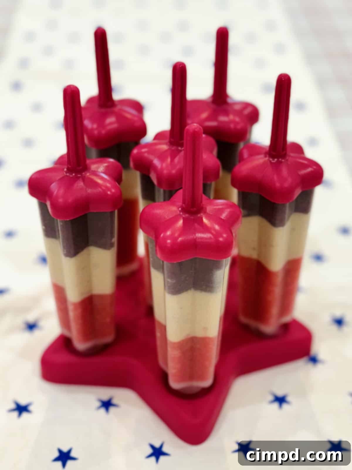 Five start shaped patriotic fruit pops artfully arranged on a star-shaped red platter.