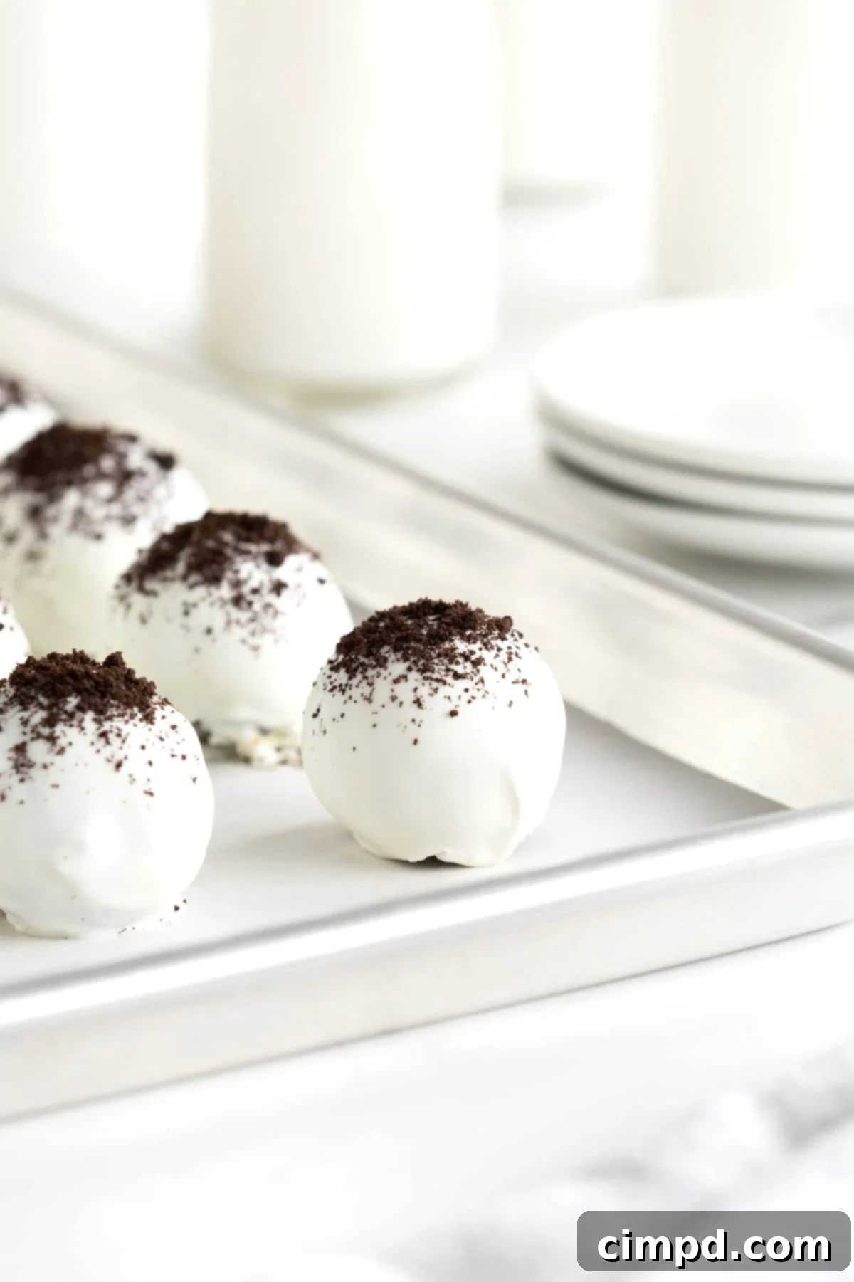 Oreo cake balls on an aluminum baking sheet lined with parchment paper.