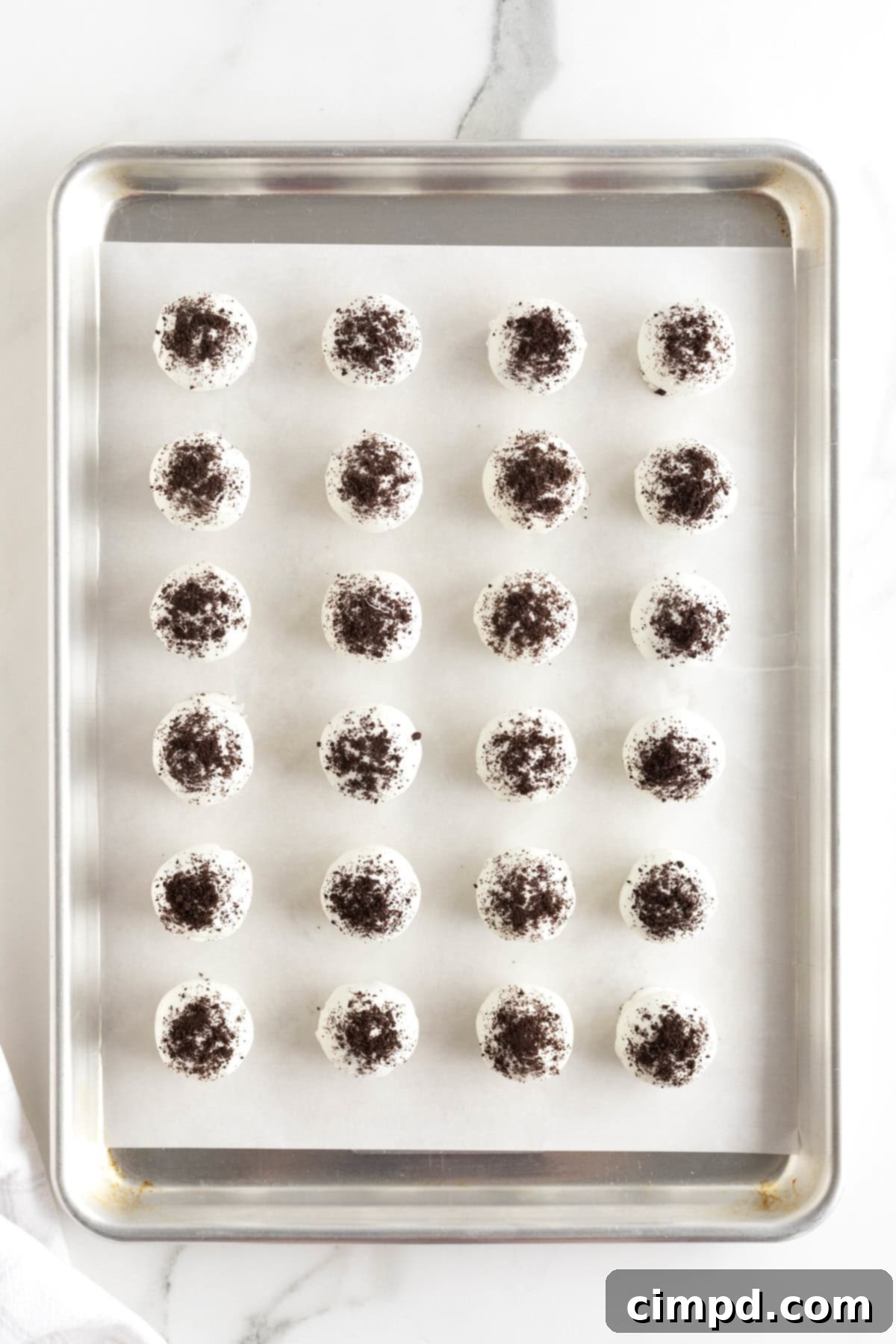 Oreo cake balls on an aluminum baking sheet lined with parchment paper.