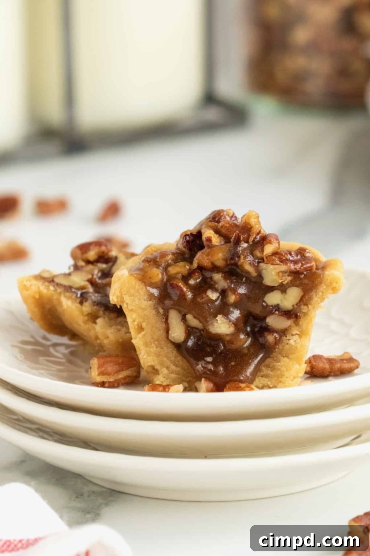 Close-up of a Pecan Pie Bite showcasing the flaky crust and rich pecan filling, on a decorative plate.