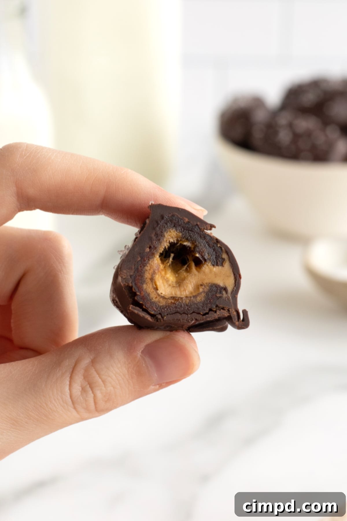 Salted Dark Chocolate Peanut Butter Stuffed Dates 3 A hand holding a peanut butter stuffed date with a bites taken out.