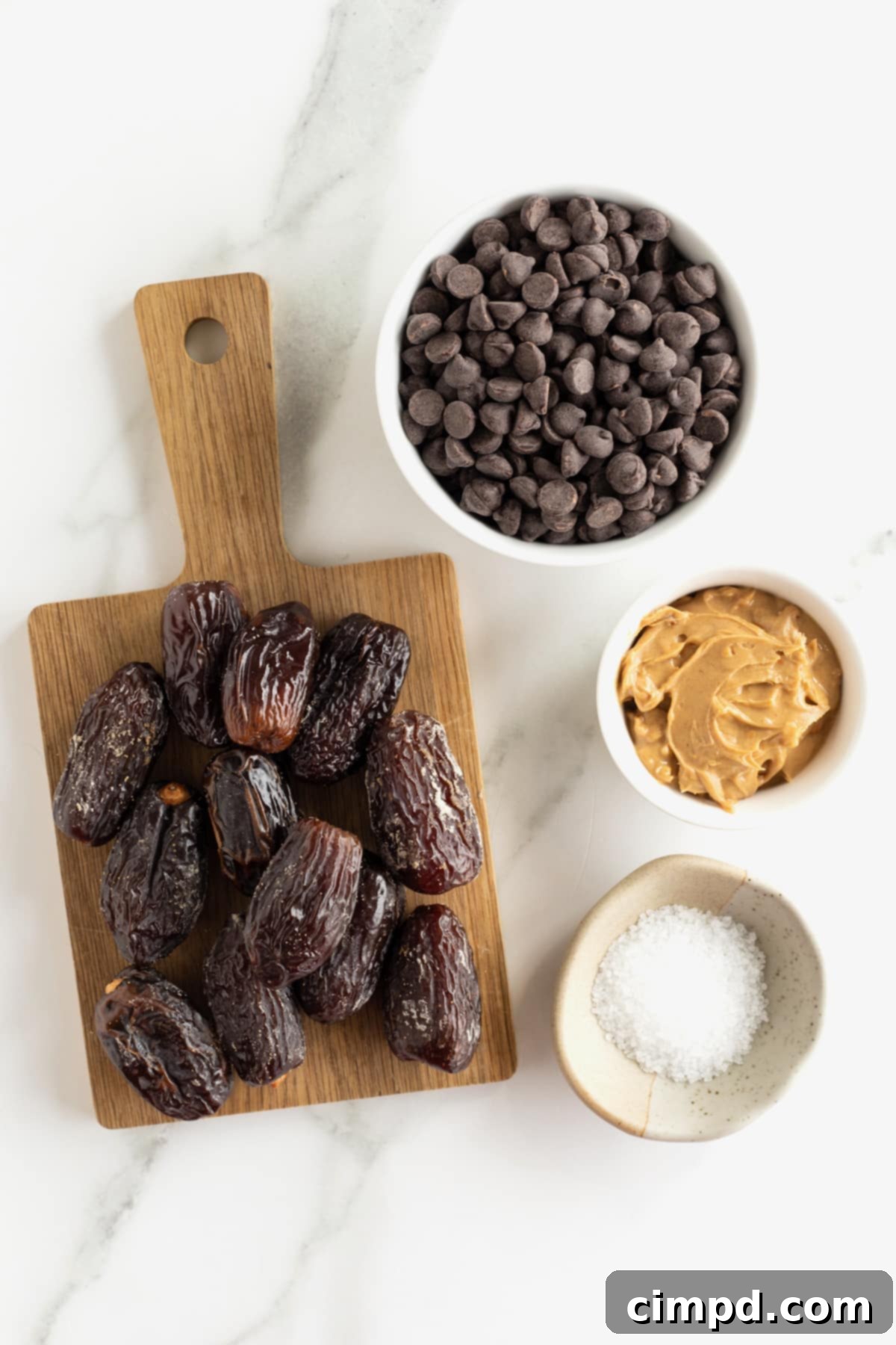 Salted Dark Chocolate Peanut Butter Stuffed Dates 6 Fresh dates on a wooded cutting board and small glass dishes of chocolate chips, peanut butter and flaky sea salt.
