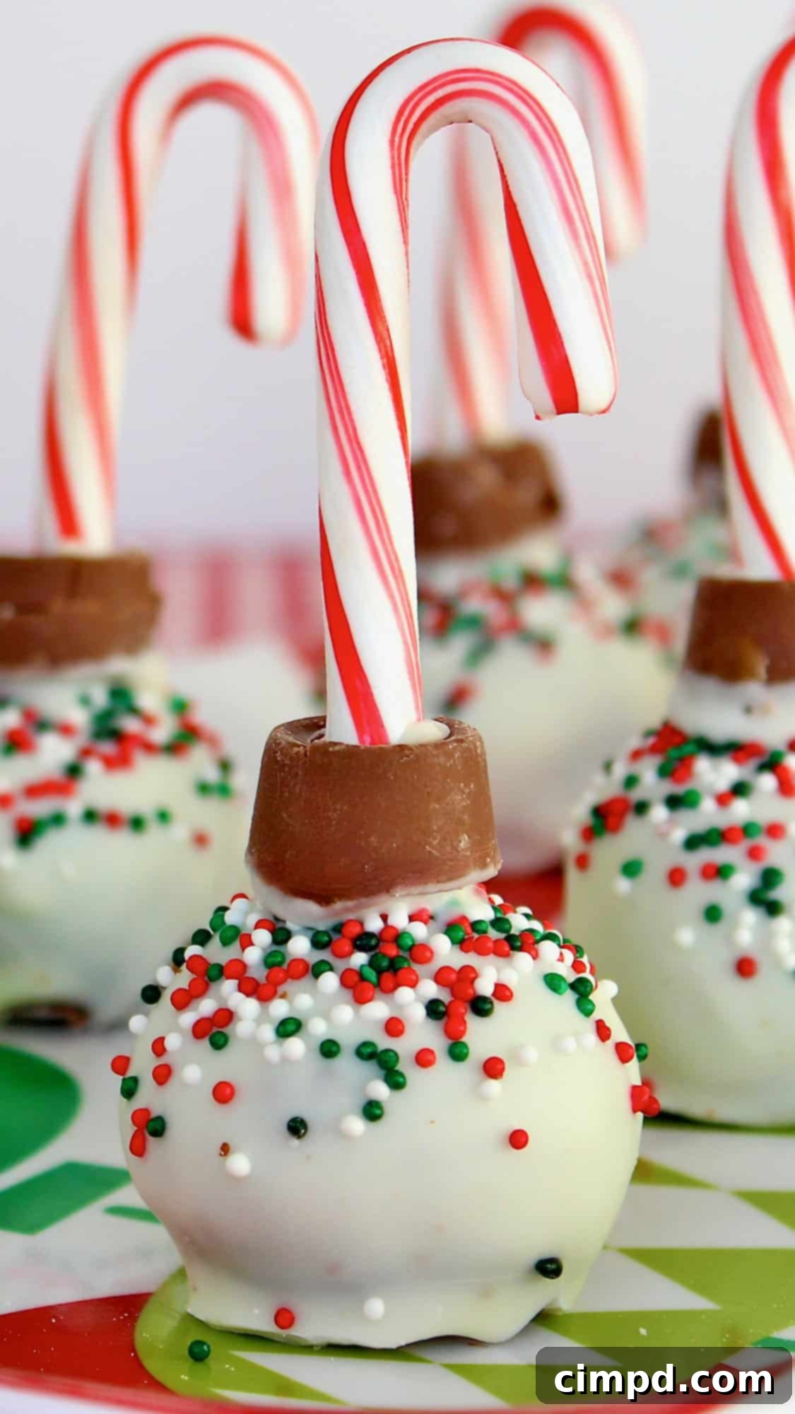 Beautifully decorated Ornament Brownie Balls with mini candy canes, arranged festively for Christmas. Each brownie ball is covered in white candy coating and adorned with colorful sprinkles.