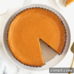 A Dark Chocolate Pumpkin Tart with a slice removed, on a white serving plate.