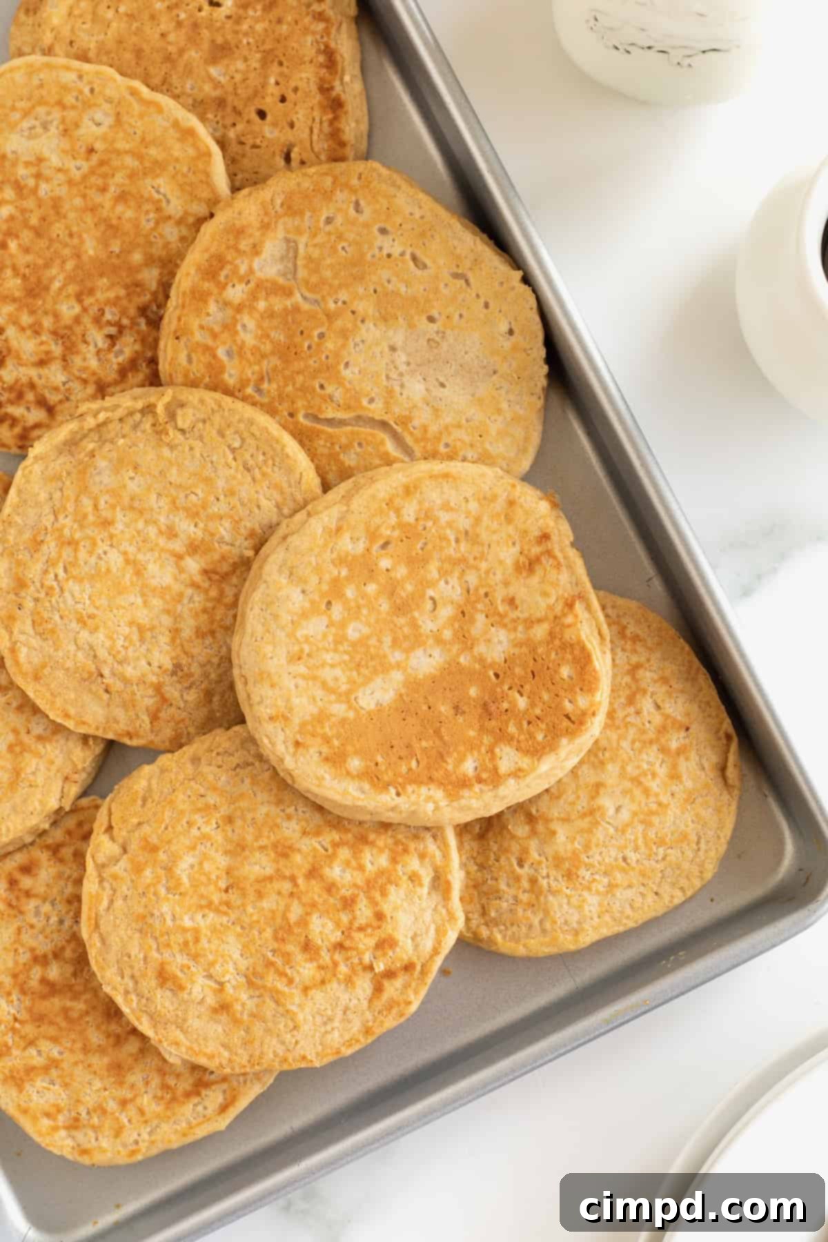 Simple 5-Ingredient Flourless Protein Pancakes 9 A metal baking sheet filled with freshly cooked flourless protein pancakes, ready for cooling or serving.
