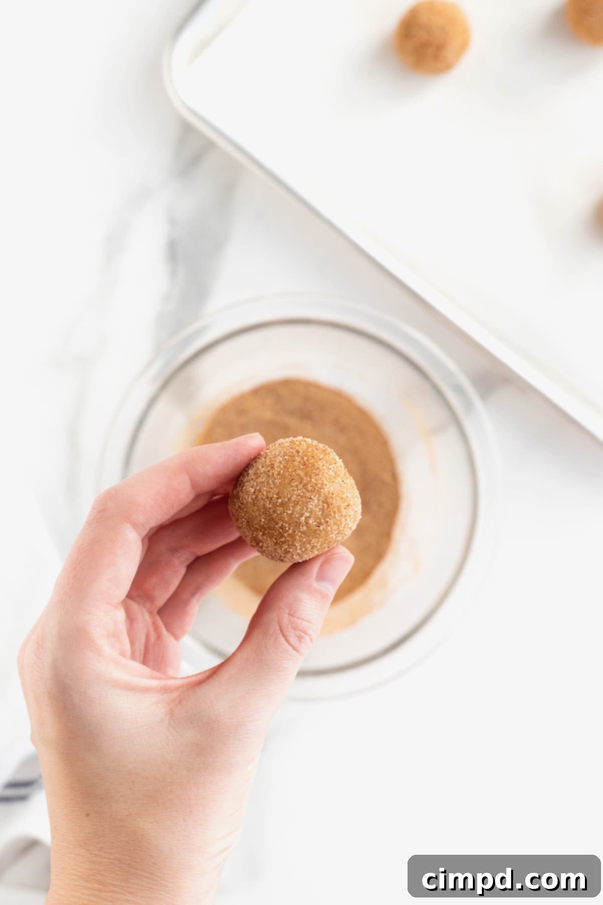 A single ball of gingerdoodle cookie dough, perfectly coated in the cinnamon-ginger-sugar mixture, ready for baking.