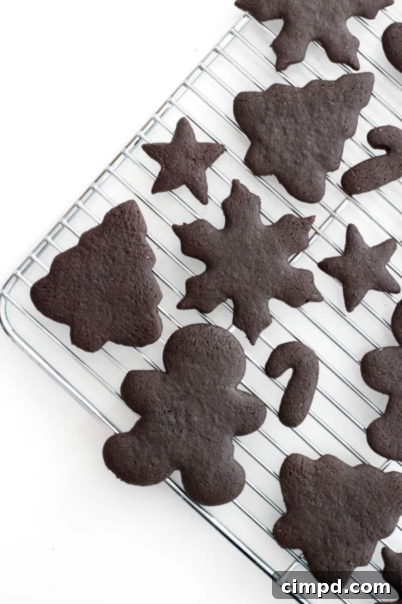 A metal cooling rack with chocolate Christmas shaped cookies of various sizes.