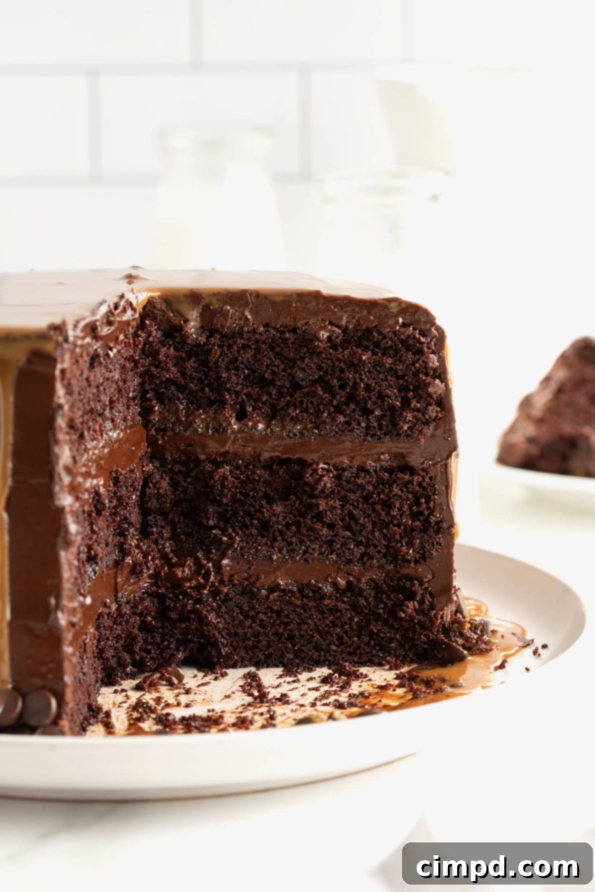 A beautifully presented chocolate three-layer cake, perfectly iced and ready for serving, resting on an elegant white serving platter.