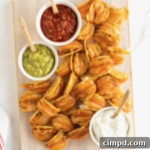Taco bites made out of tortilla chips, refried beans and cheese served with a bowl of guacamole, sour cream and a bowl of salsa.