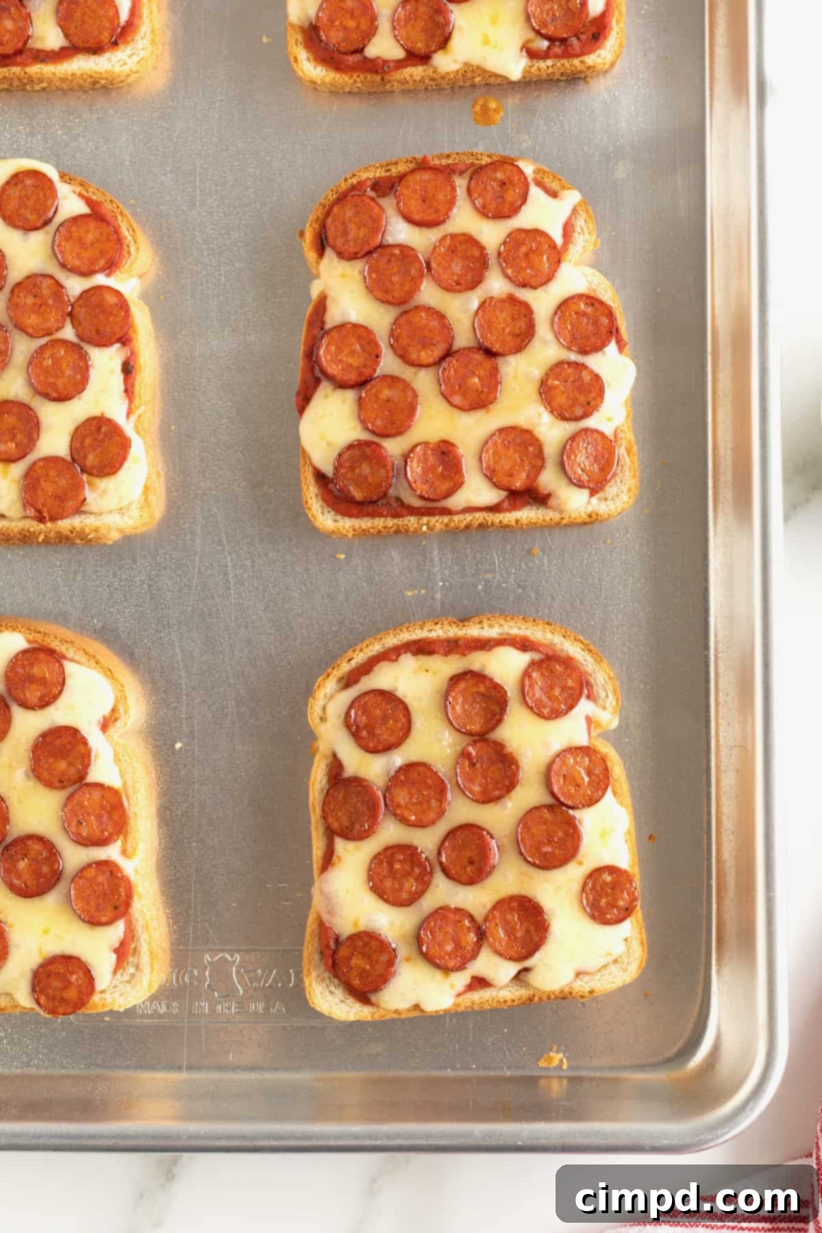 Six slices of perfectly reheated pizza toast, golden and cheesy, arranged on an aluminum baking sheet.