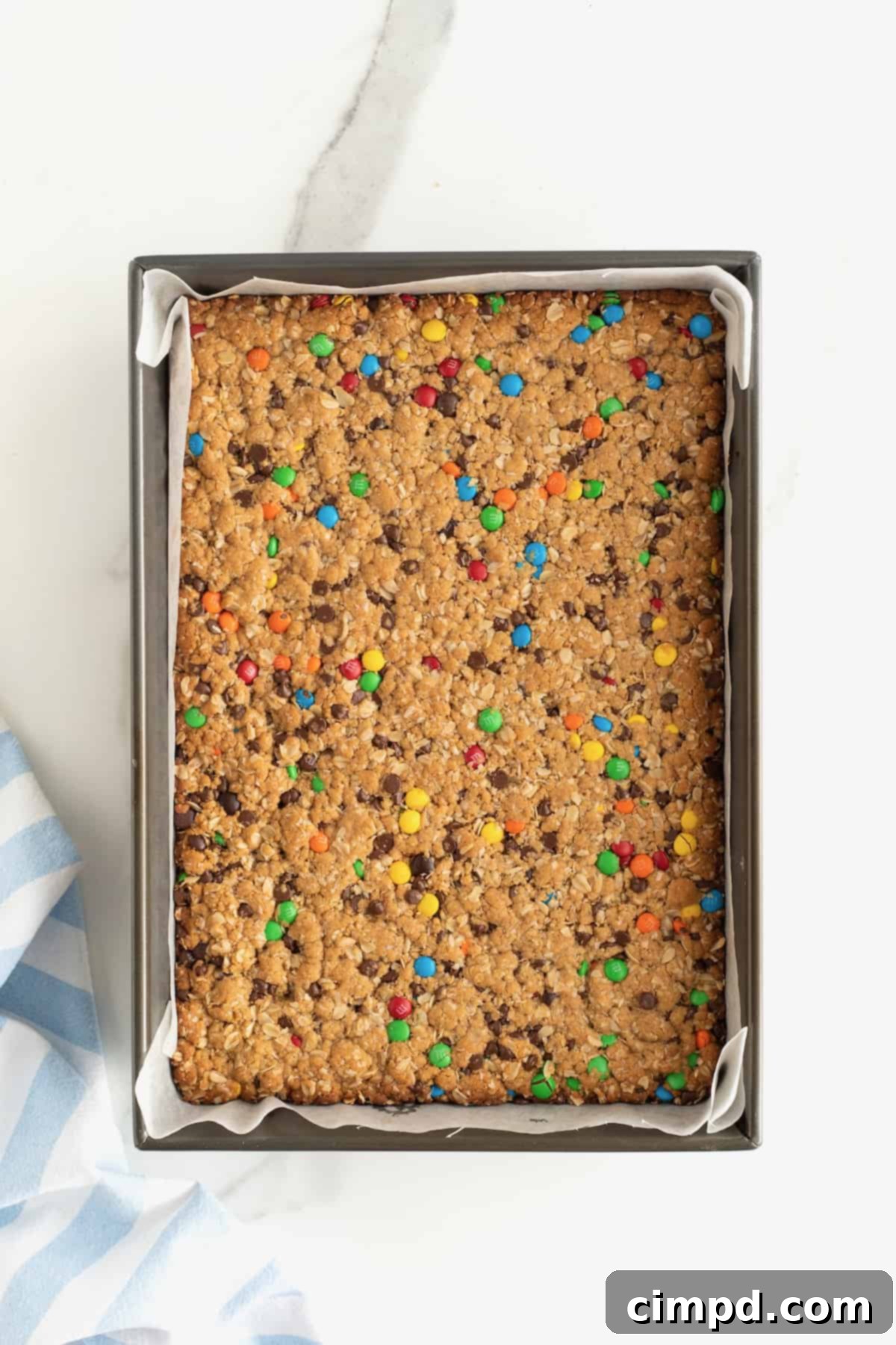 A panoramic shot of a baking pan filled with golden-brown monster cookie bars, fresh out of the oven.