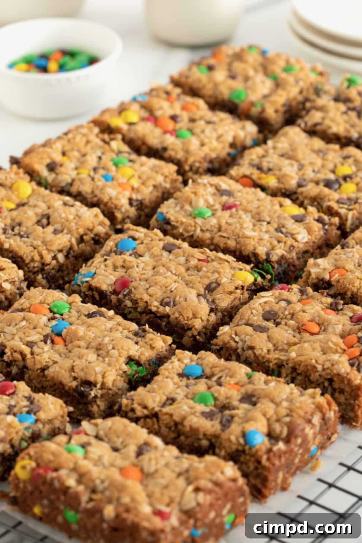 Close-up of freshly baked Flourless Monster Cookie Bars with mini M&Ms scattered in the background, showcasing their vibrant colors and tempting texture.