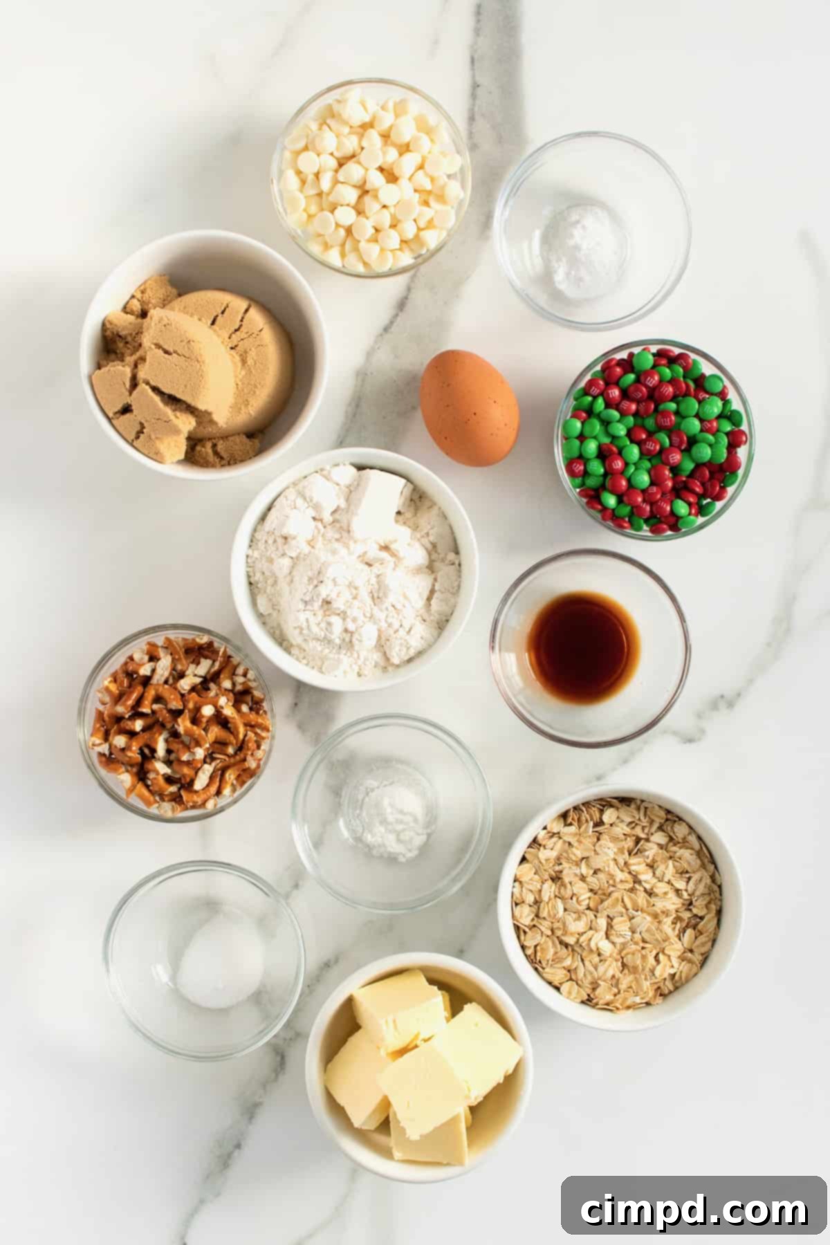 Ingredients for Sleigh Mix Cookies laid out on a kitchen counter, including flour, oats, M&Ms, and pretzels.