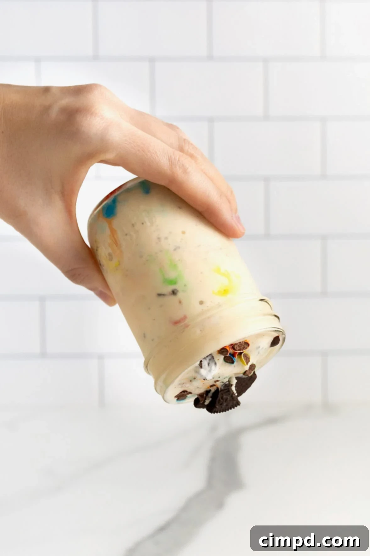 A hand holding a mason jar of homemade blizzard upside down, demonstrating its thick consistency and readiness for the famous test.