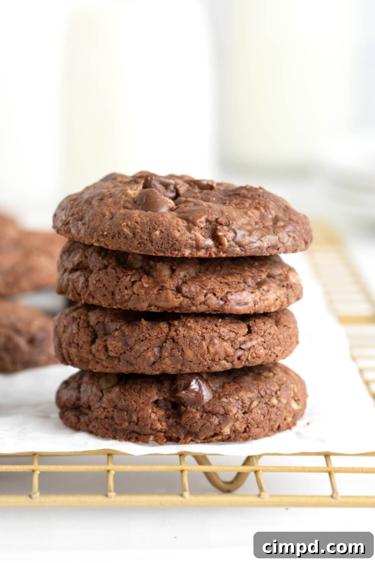 Four flourless Nutella cookies in a stack on a parchment lined cooling rack.