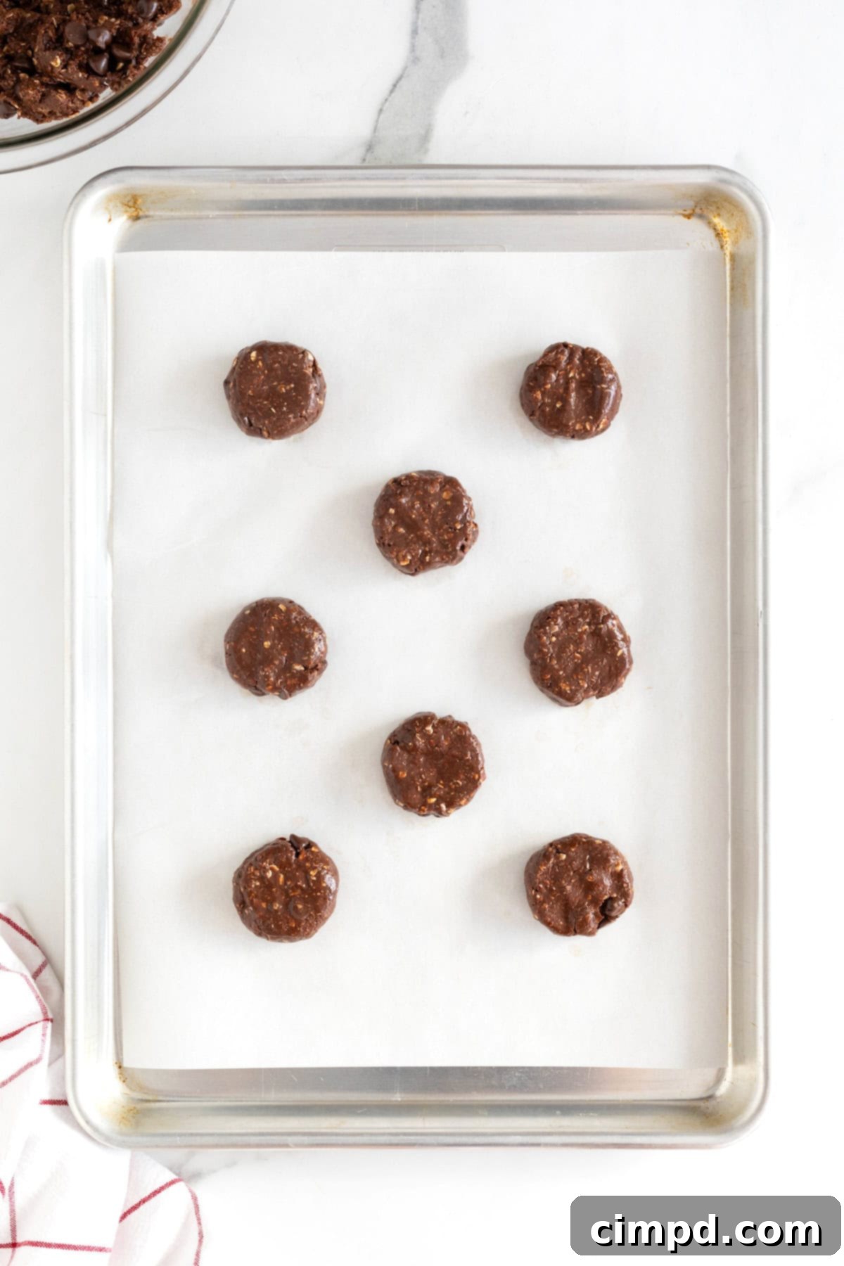 Eight Nutella cookie dough balls on a parchment lined cookie sheet.