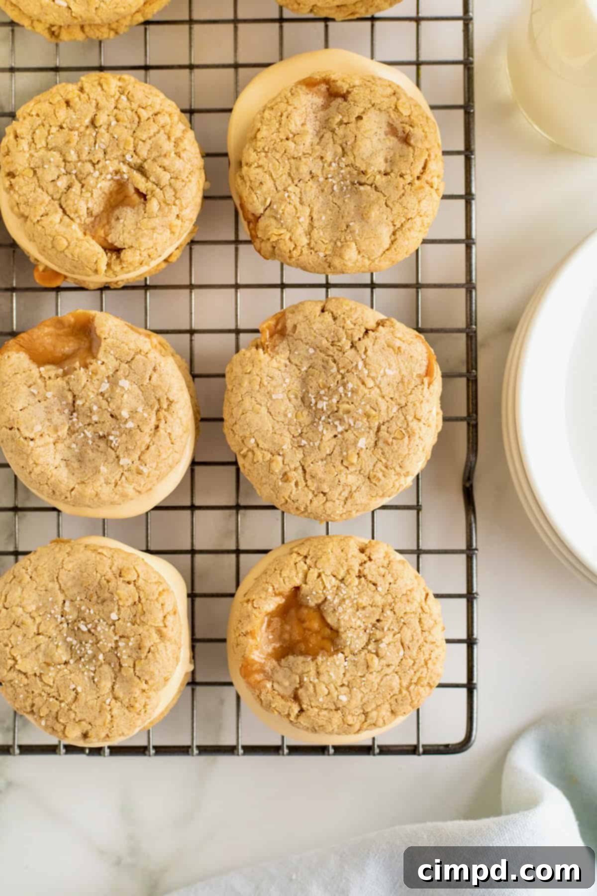 Irresistible Salted Caramel Oatmeal Cream Pies 10 An overhead shot of six perfectly baked and assembled salted caramel oatmeal cream pies lined up neatly on a wire cooling rack, ready for storage or serving.