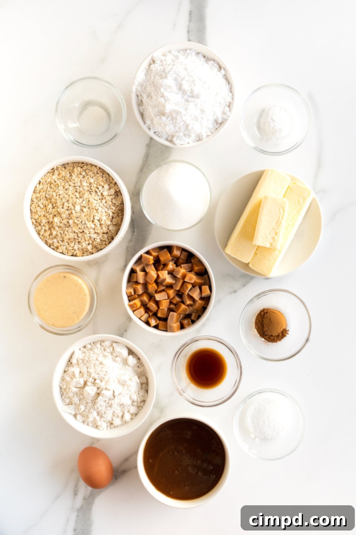 All the fresh ingredients neatly arranged in small glass dishes on a pristine white counter, ready for baking salted caramel cream pies.