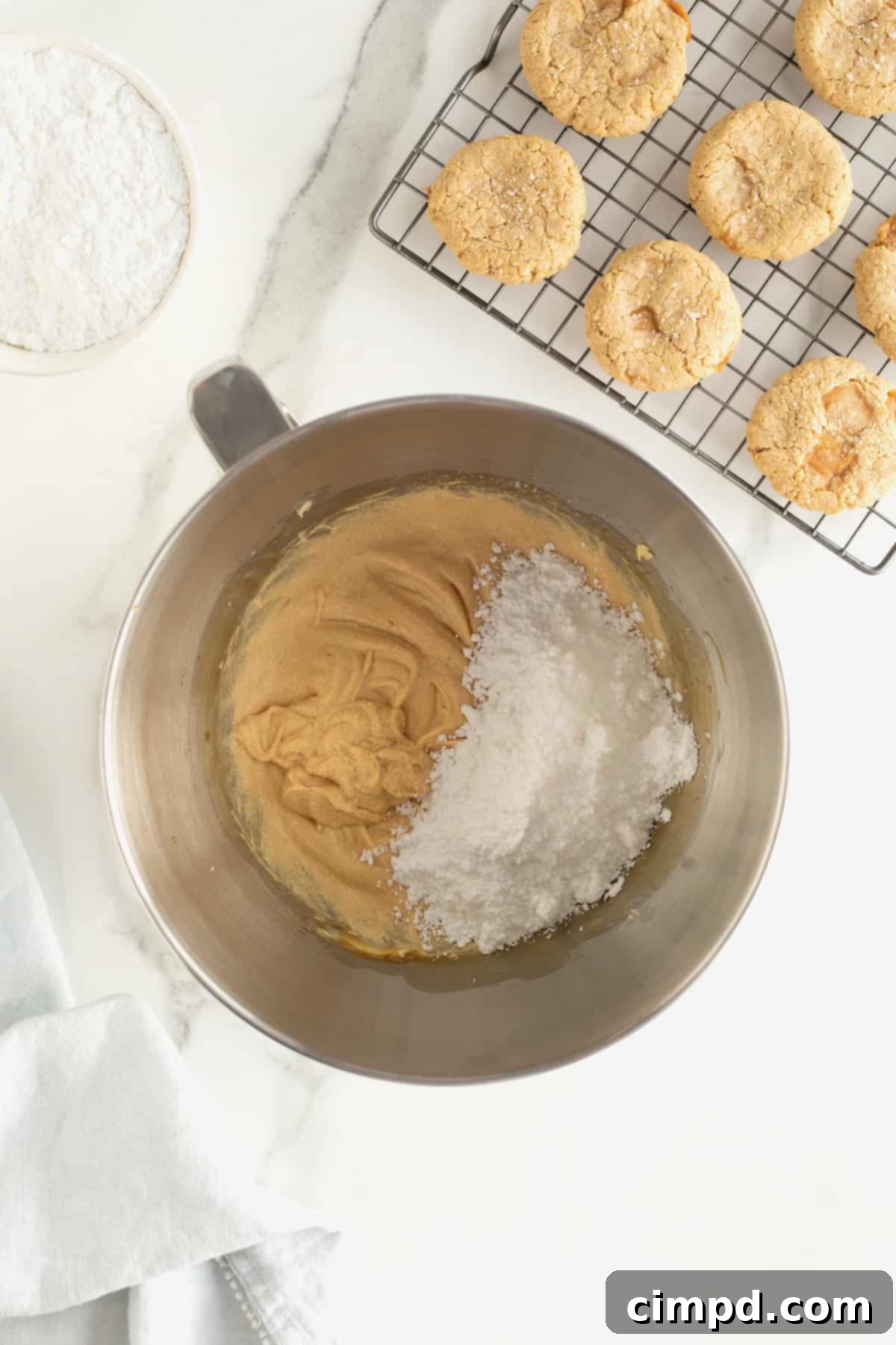 A mixing bowl with creamy filling, with powdered sugar being added to achieve the perfect consistency.