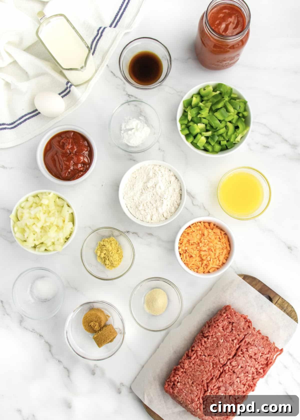 Sloppy Joe Supper Bake 4 A collection of fresh ingredients laid out for making Sloppy Joe Casserole, including ground beef, vegetables, sauces, and cheese.