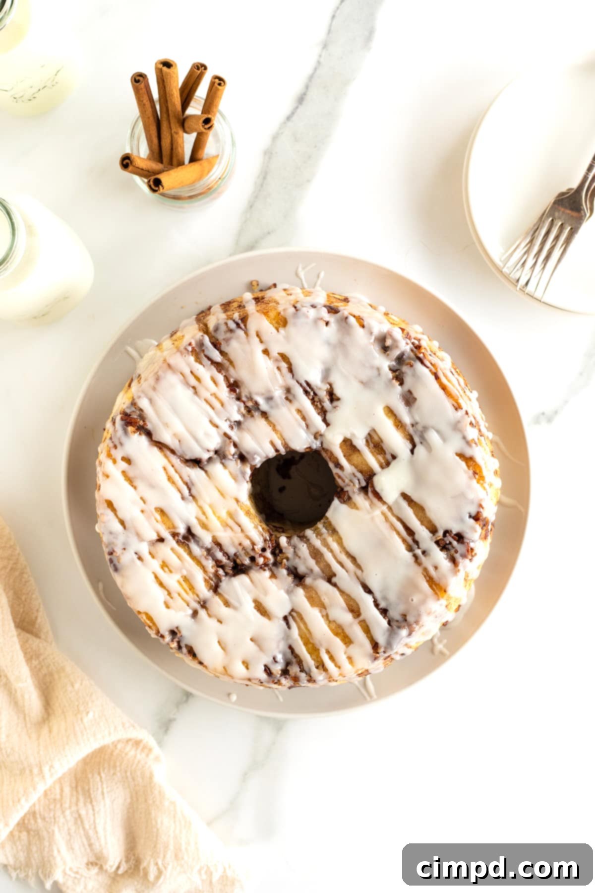 Easy Overnight Sweet Rolls 11 Sweet rolls on a round white serving plate with white glaze drizzled over them.