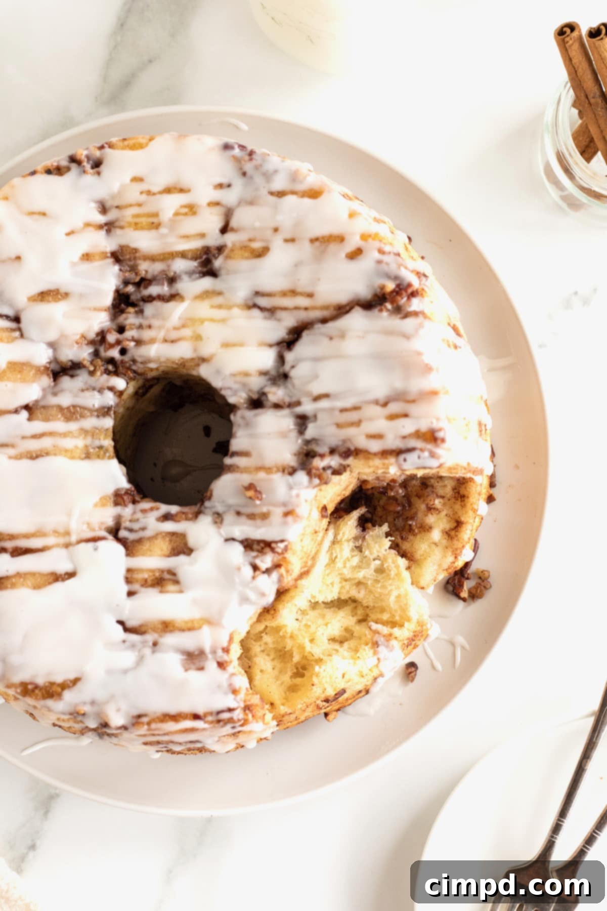 Easy Overnight Sweet Rolls 4 Sweet rolls on a round white serving plate with white glaze drizzled over them.