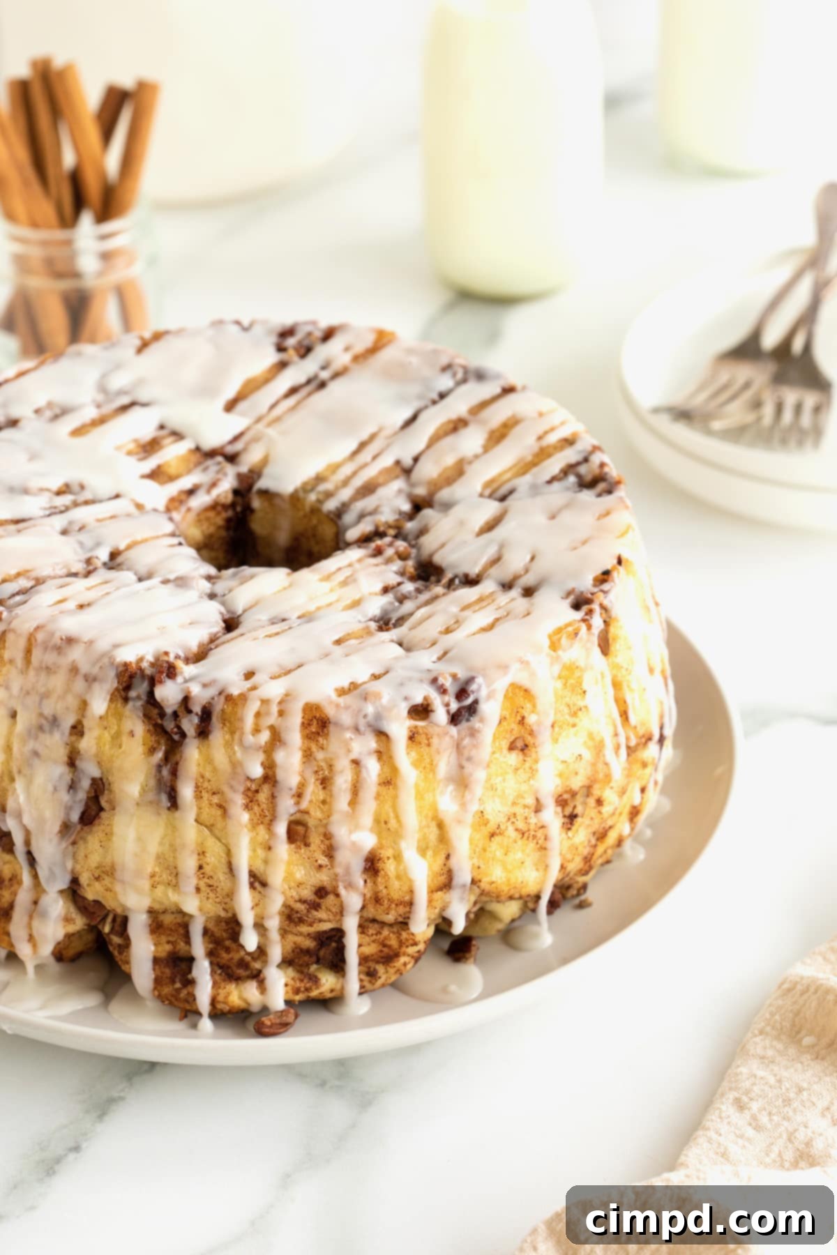 Easy Overnight Sweet Rolls 5 Sweet rolls on a round white serving plate with white glaze drizzled over them.