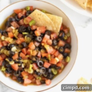 A large white serving bowl with a gold rim filled with colorful harlequin dip.