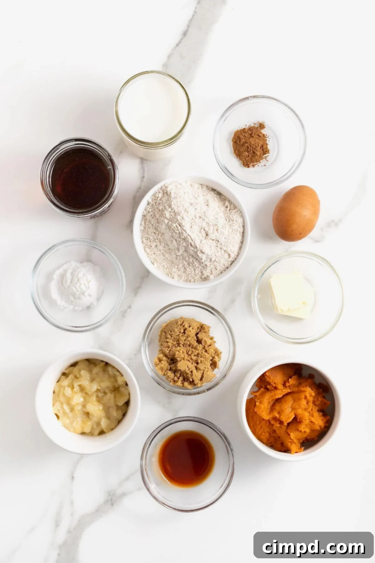 Autumn Pumpkin Banana Pancakes with Pumpkin Spice Drizzle 7 Ingredients to make pumpkin banana pancakes in small glass dishes on a white marble counter.