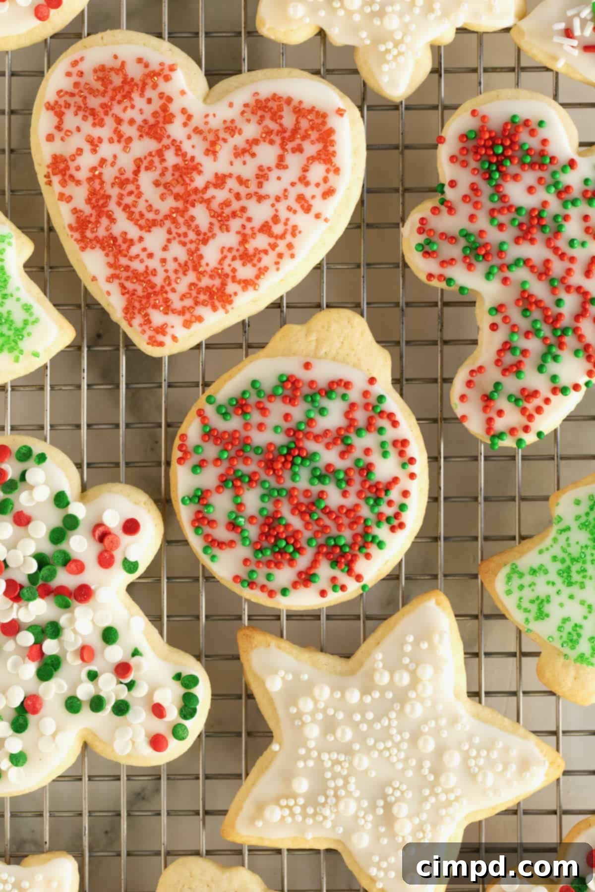 Iced holiday sugar cookies with red and green sprinkles on a wire cooling rack.
