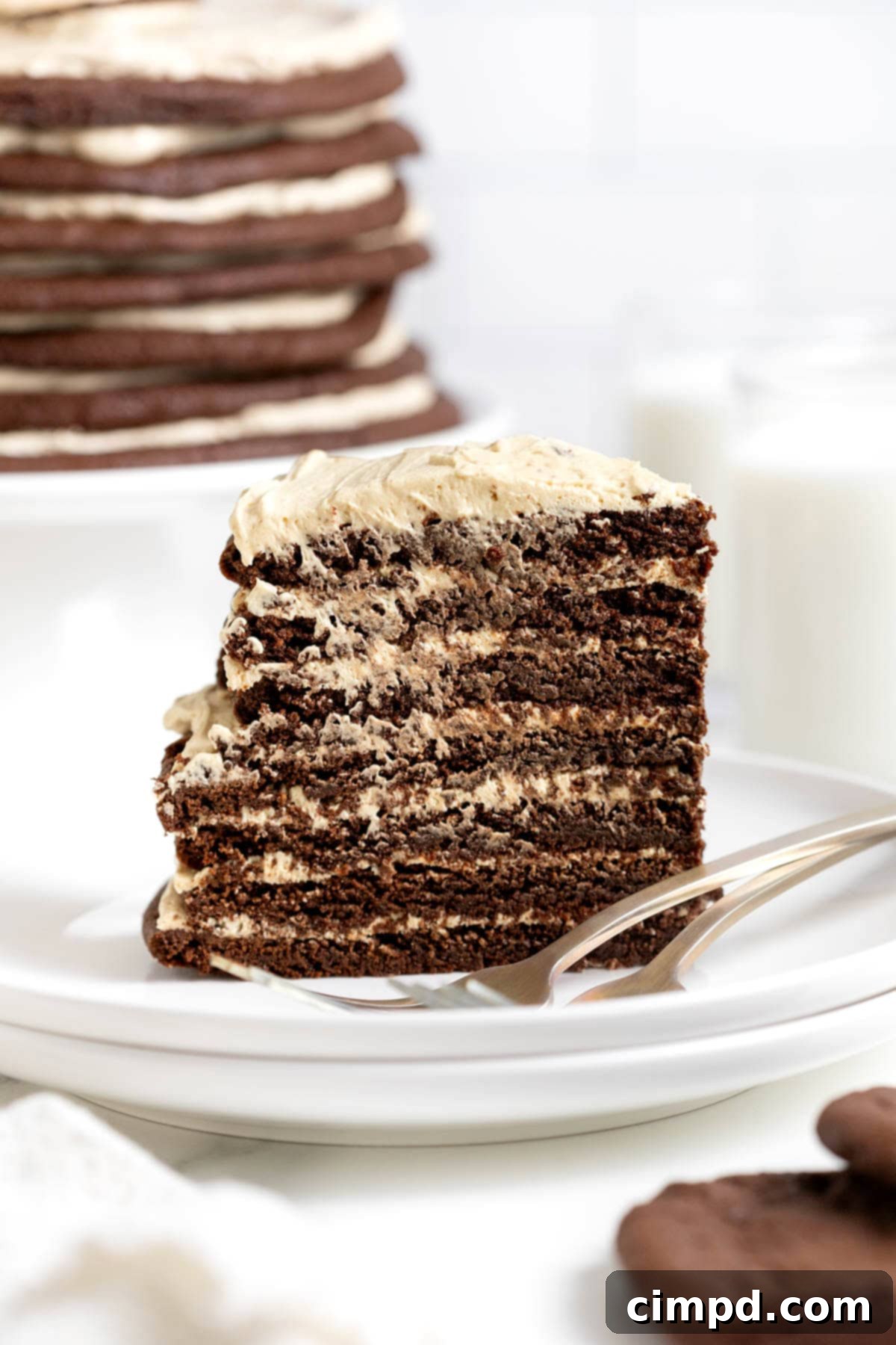 Decadent Peanut Butter Chocolate Cookie Tower 13 A perfectly cut slice of chocolate peanut butter cookie layer cake on a white plate next to a fork, ready to be enjoyed.