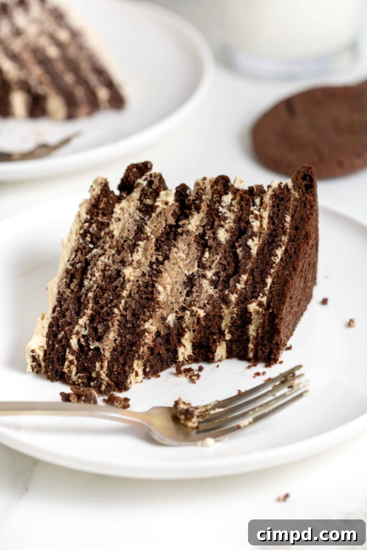 Decadent Peanut Butter Chocolate Cookie Tower 3 A delectable slice of the chocolate peanut butter layered cookie cake, placed on a white plate with a fork, revealing the rich chocolate cookie layers and creamy peanut butter filling.