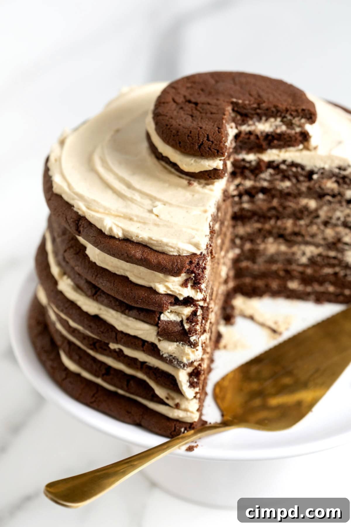 Decadent Peanut Butter Chocolate Cookie Tower 4 The magnificent chocolate layer cake with creamy peanut butter frosting, presented on a white cake stand with several slices already removed, and a metal pastry server resting nearby.