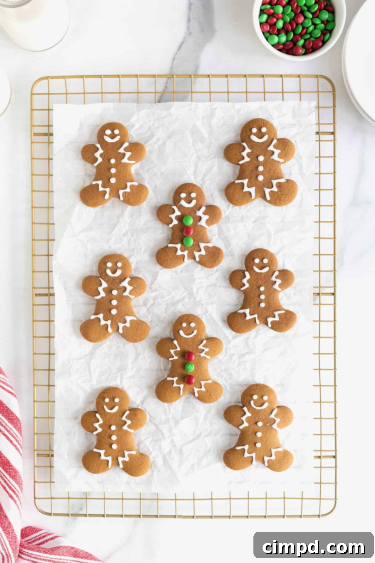 Spiced Gingerbread Delights 10 Eight decorated gingerbread men cookies on a parchment lined gold toned cooling rack.