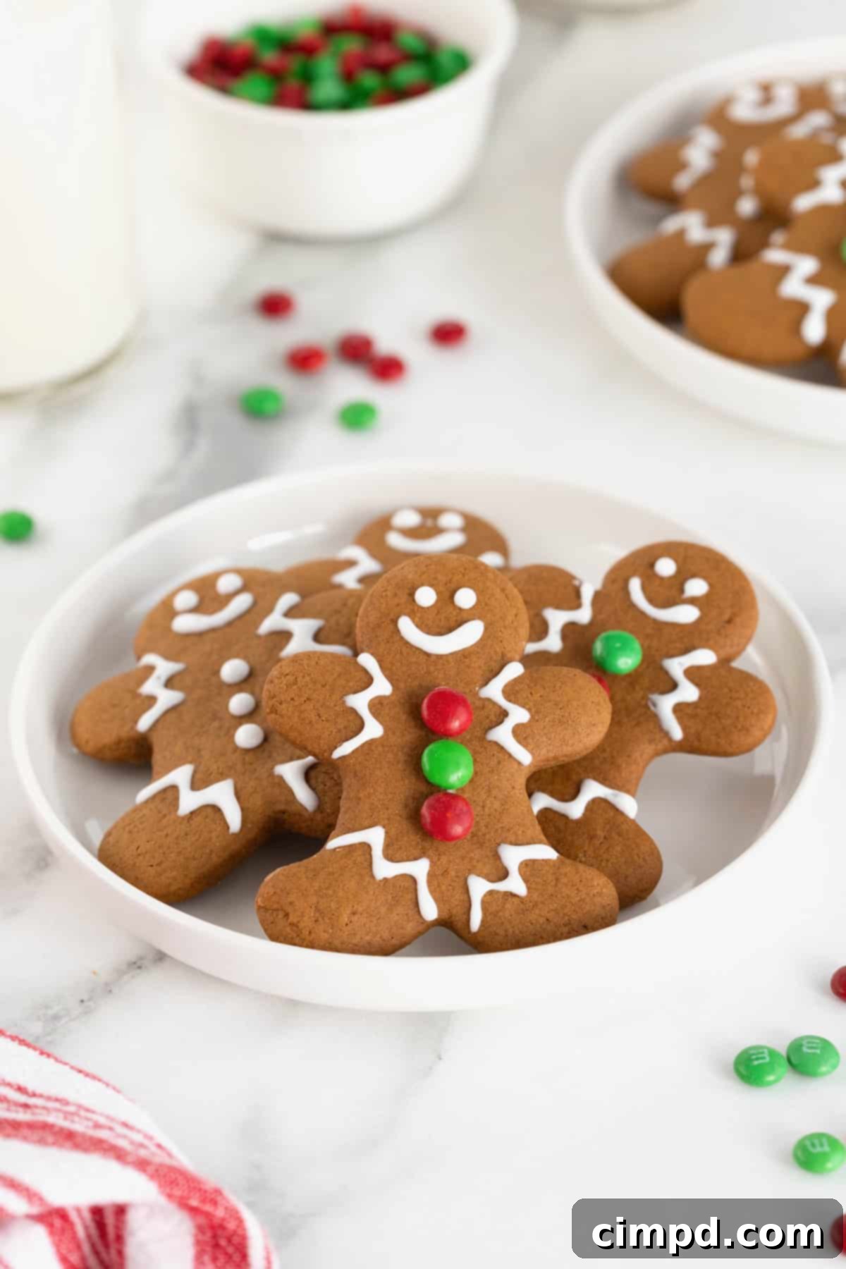 Spiced Gingerbread Delights 11 A pile of gingerbread men cookies on a white plate on a white marble counter.