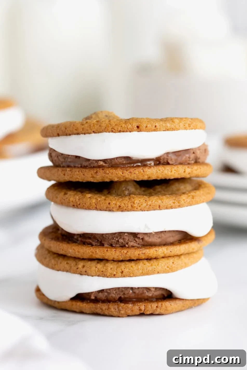 A stack of three s'mores ice cream sandwiches on a white marble surface.