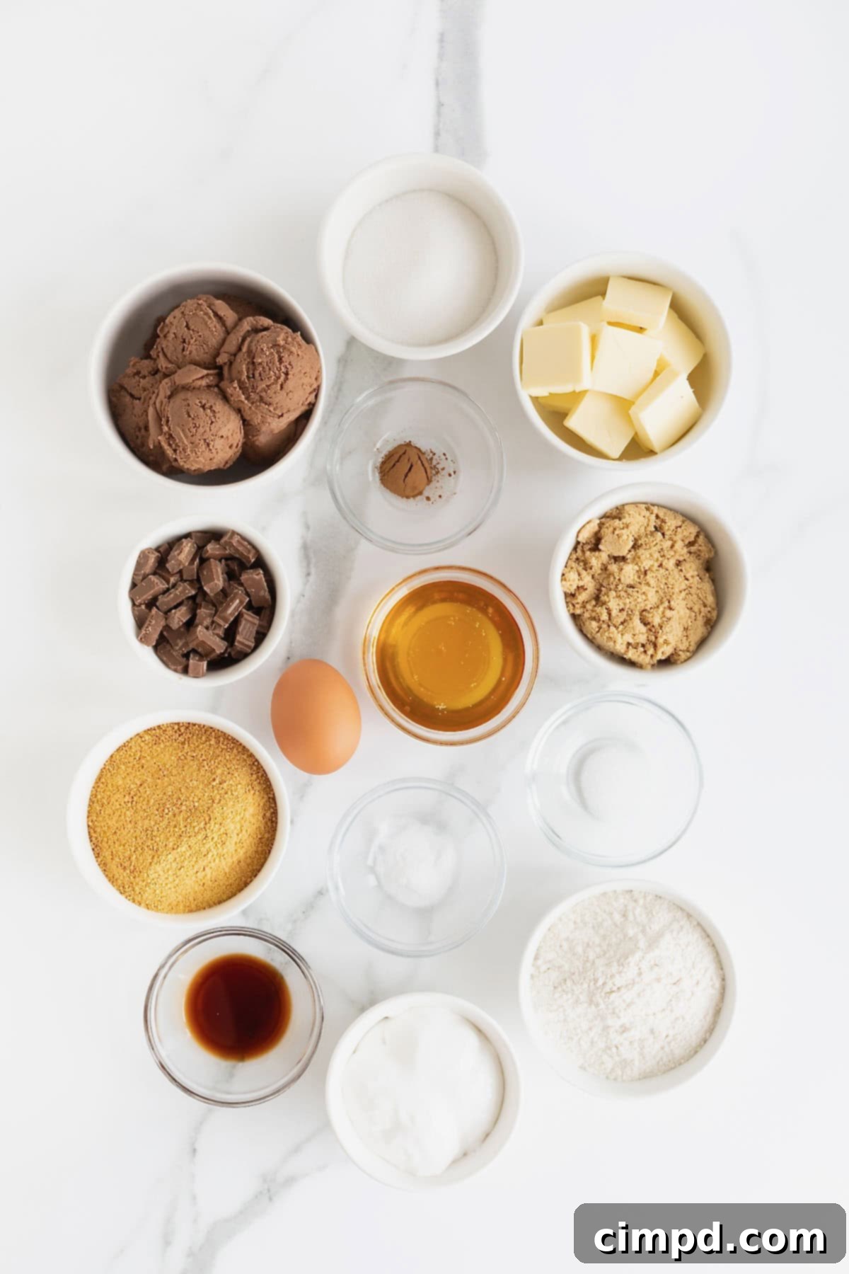 Ingredients to make s'mores ice cream sandwiches in small glass dishes on a white marble counter.