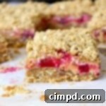 A close-up shot of a single plum crumb bar with a golden topping and visible plum filling