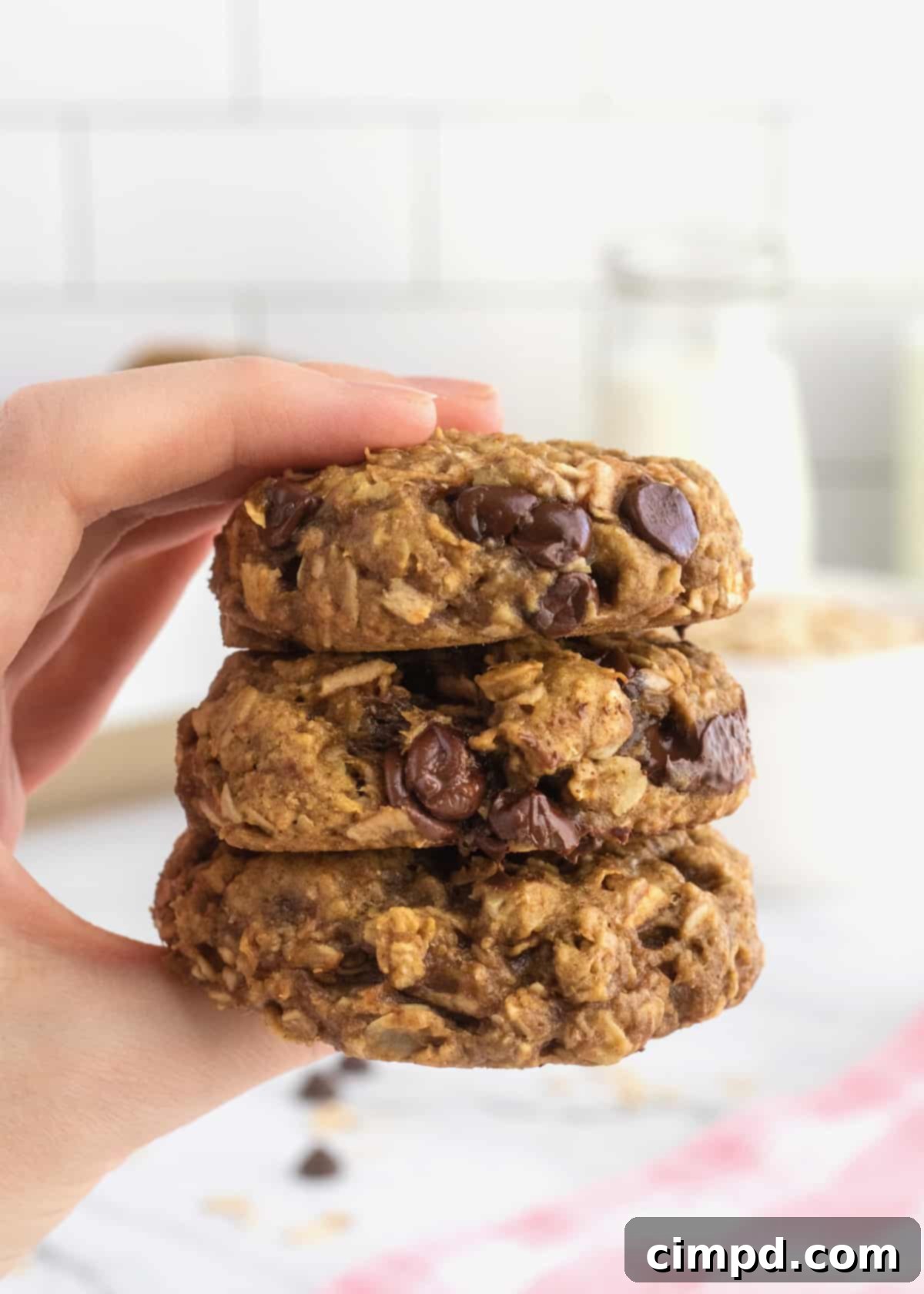 A hand holding three Breakfast Cookies stacked on top of each other.