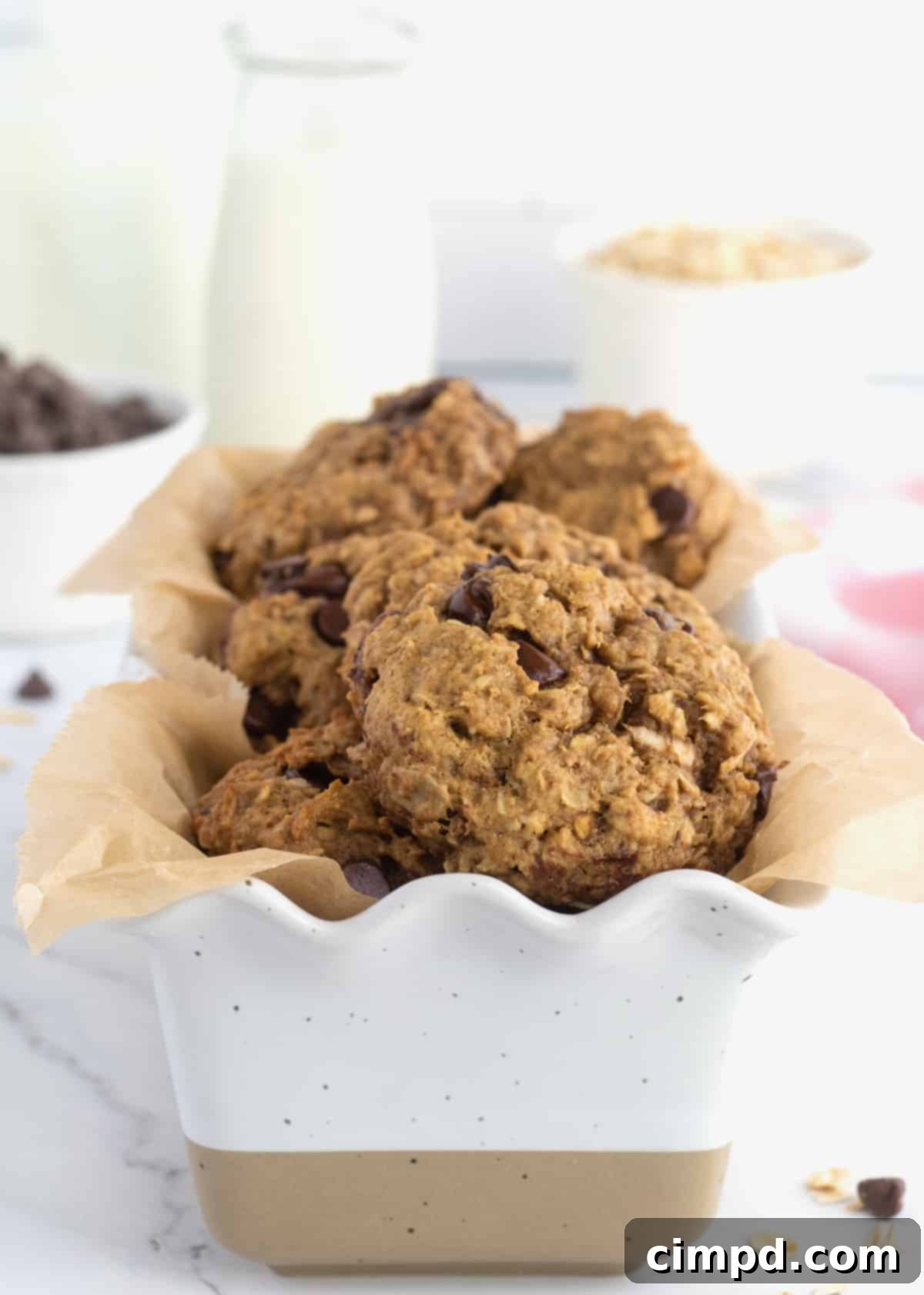 A white loaf-shaped baking dish with scalloped edges lined with wax paper and filled with Breakfast Cookies.