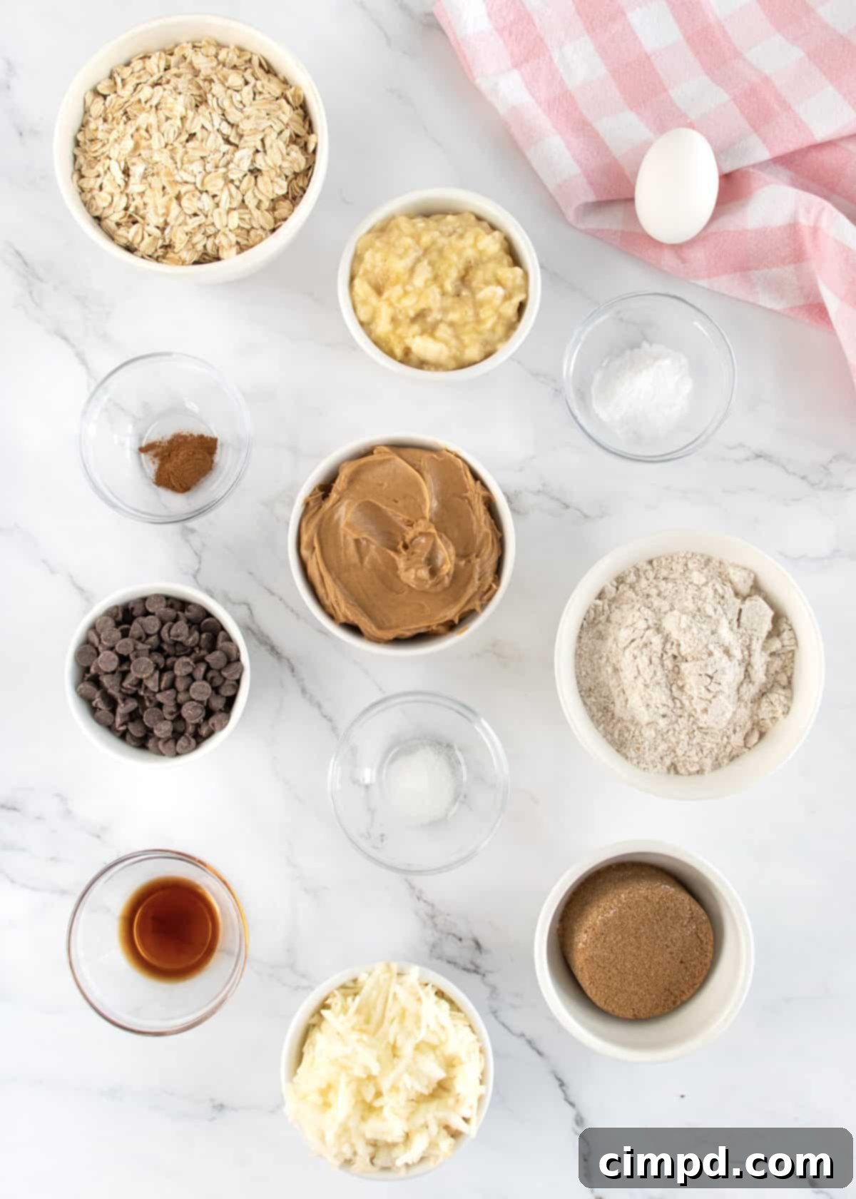 Ingredients to make Breakfast Cookies in small glass dishes on a white marble counter.